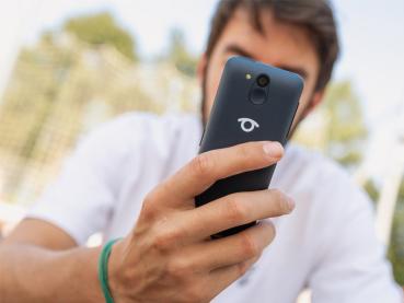 Mann mit weißem Shirt hält das Telefon in der Hand