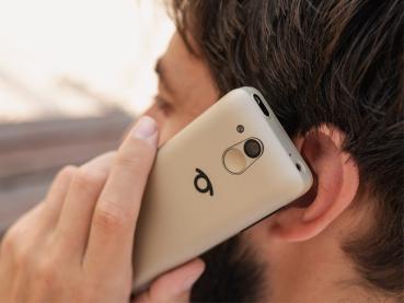 Mann mit weißem Shirt hält das Telefon in der Hand und telefoniert